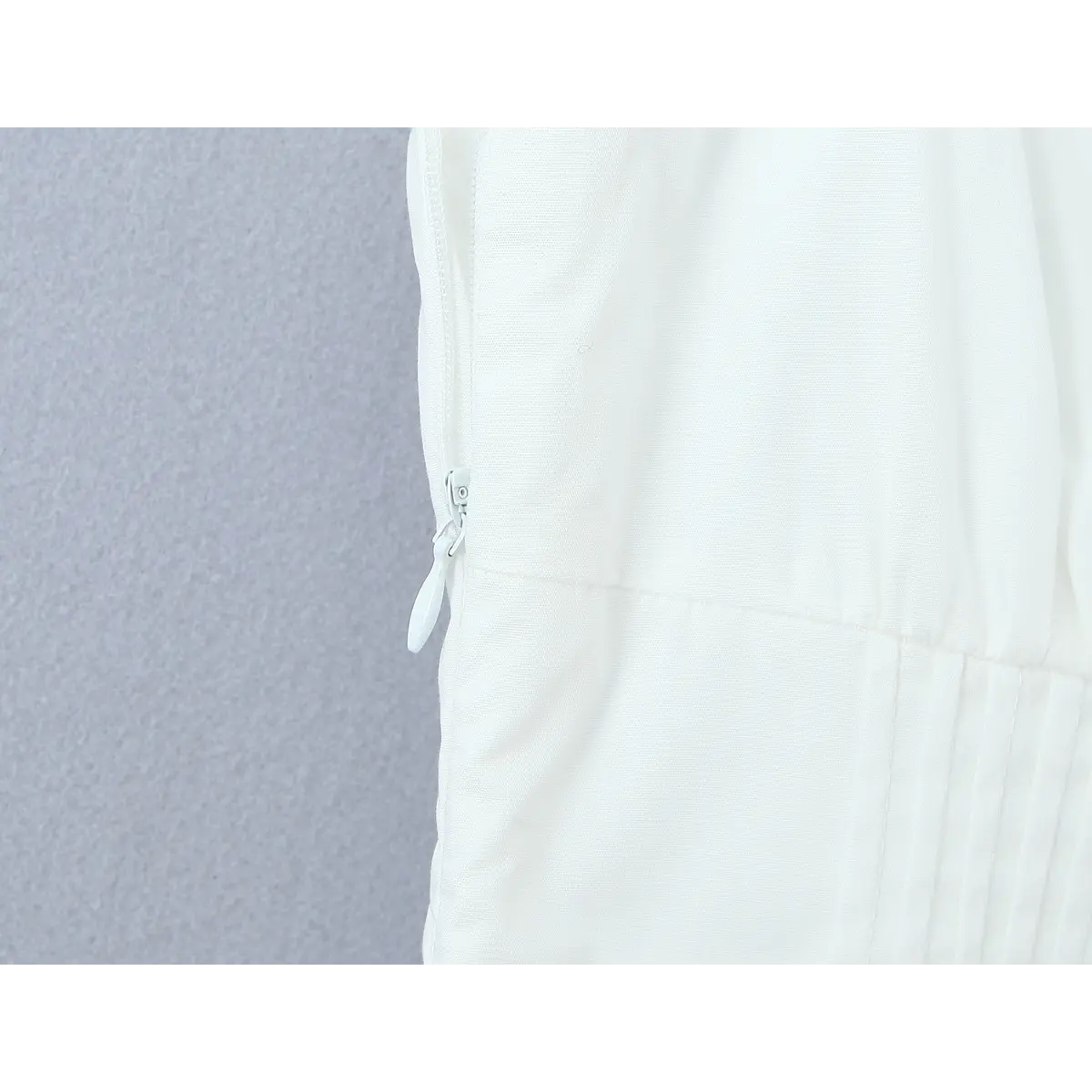 Close-up of the invisible side zipper on the white dress, showing the pull tab and stitching