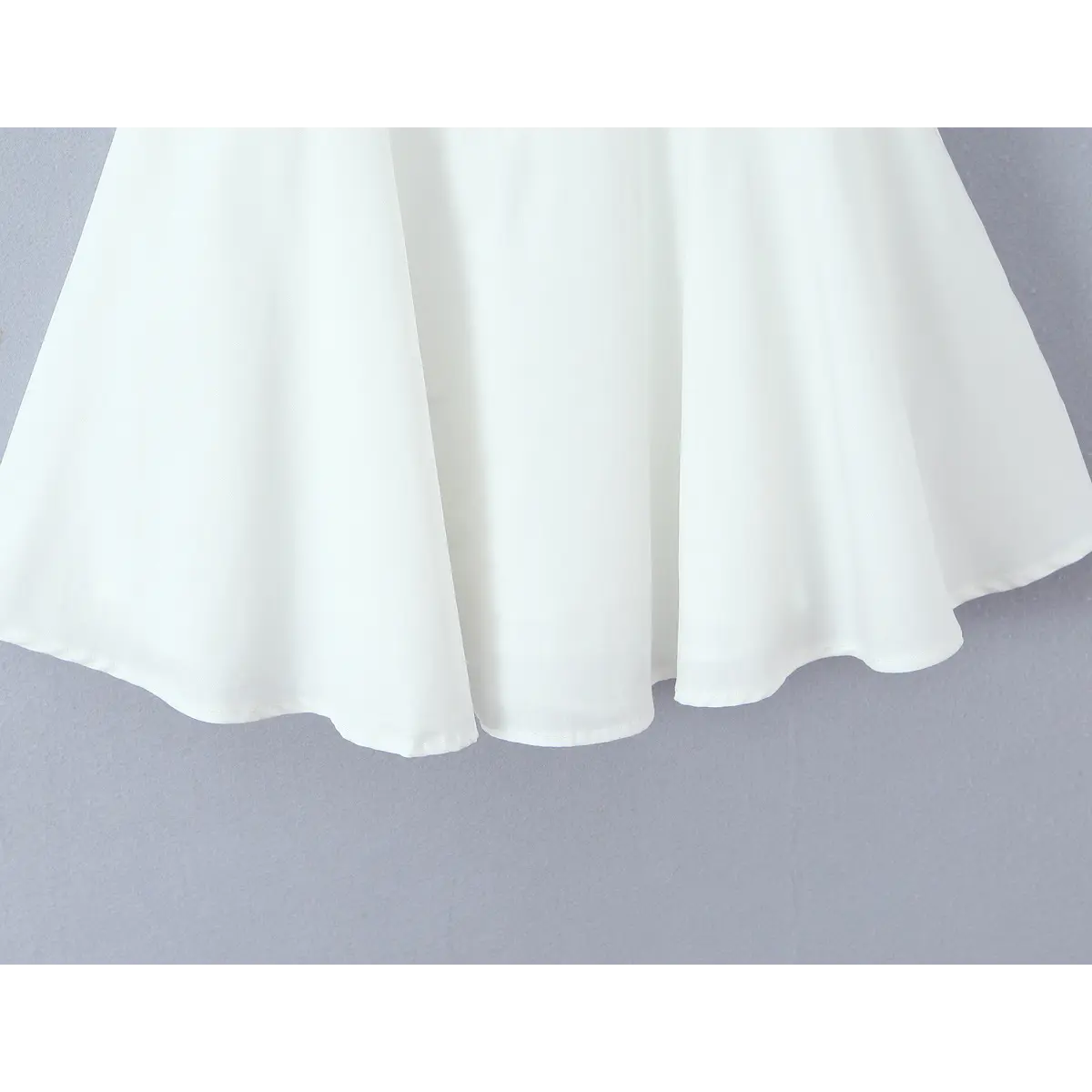 Close-up of the flared skirt hem, showing the smooth A-line silhouette and clean stitching