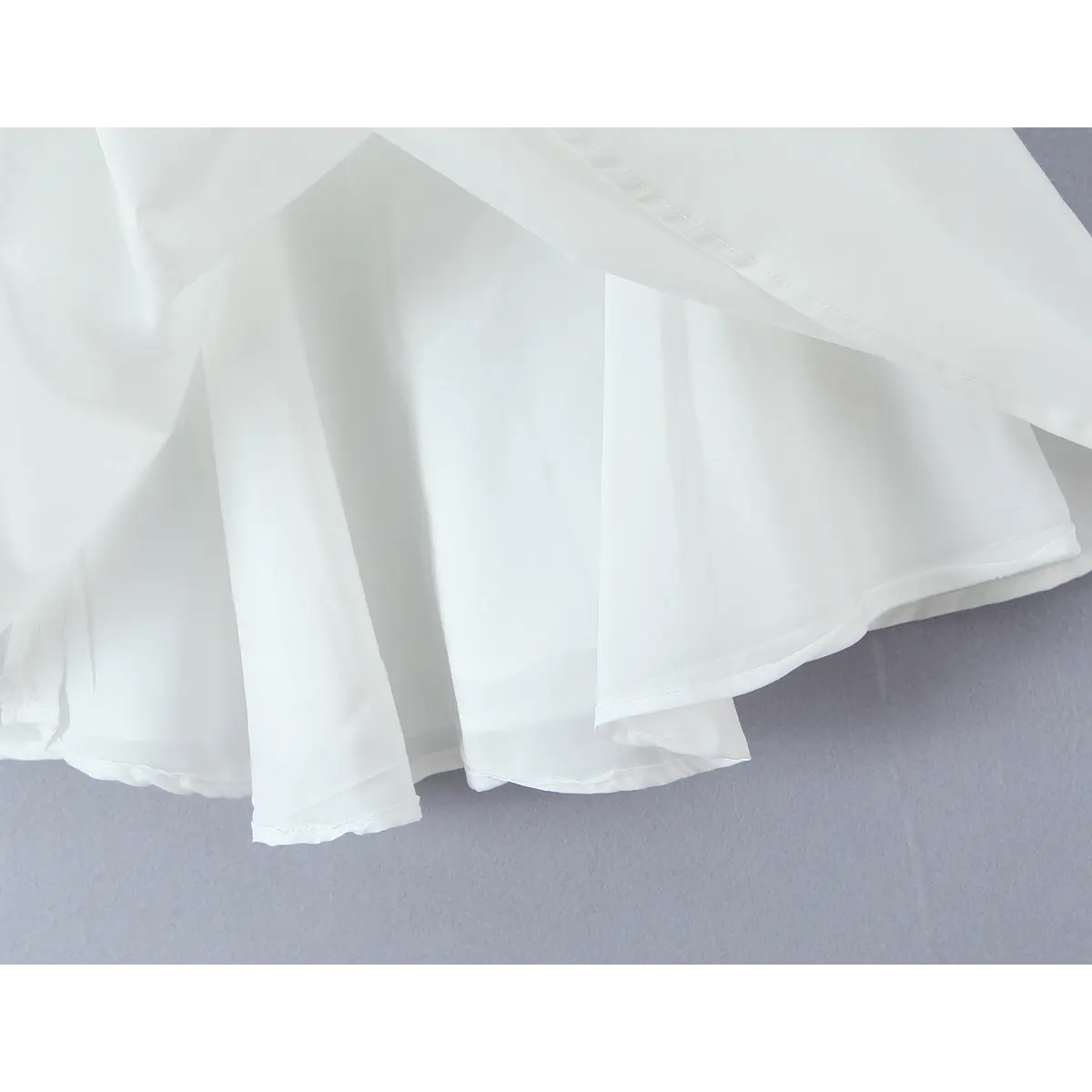 Close-up of the white dress's skirt hem, showing double-layer lining and flared chiffon fabric