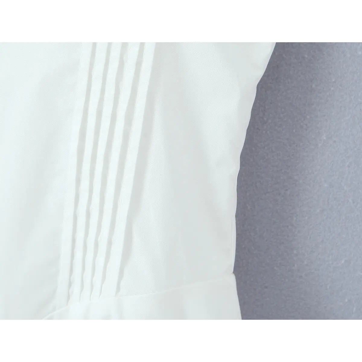 Close-up of the corset-style pintuck pleats on the dress's waist panel, creating a slimming effect