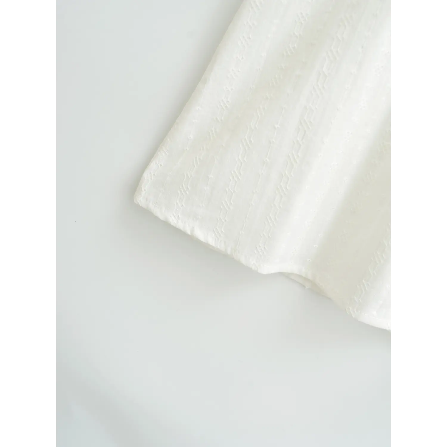 Close-up of the finished hem on a white textured camisole top