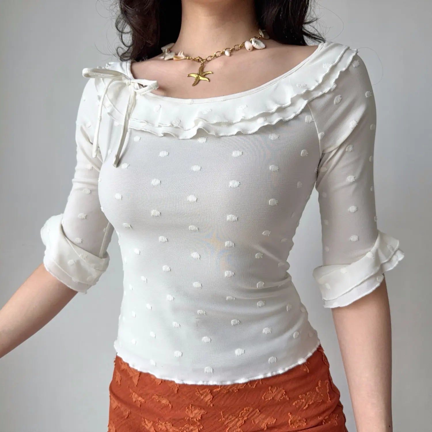 Front lifestyle shot on model of white mesh slim blouse, raised dot fabric, double ruffle neck, side bow detail, rolled flared cuff sleeves