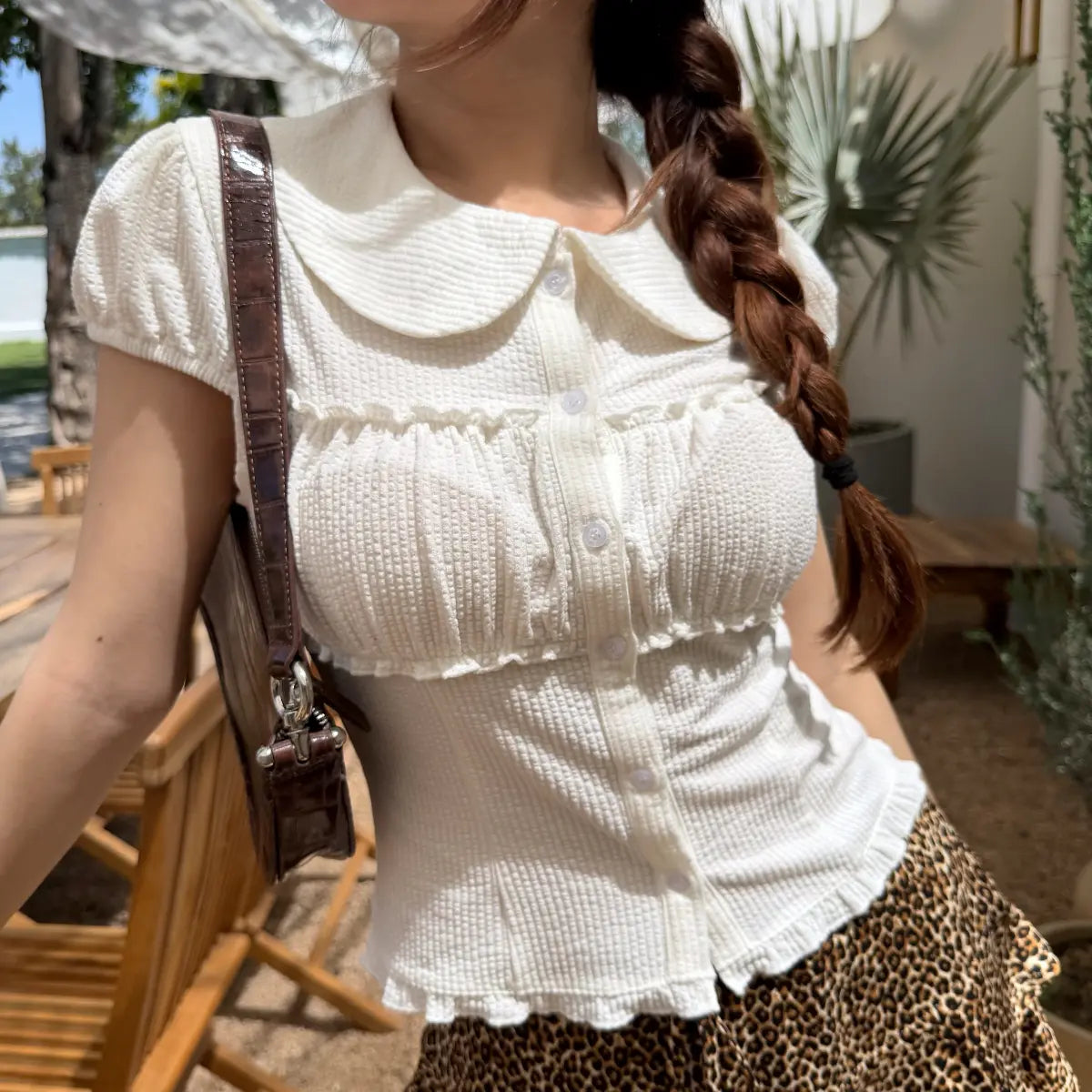 The same white top styled with a leopard-print ruffled mini skirt, showing the full outfit look.
