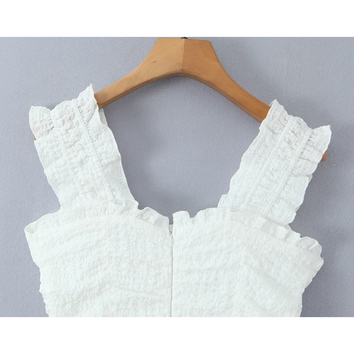 Back view of the white dress, highlighting the ruffled straps and central zipper closure.