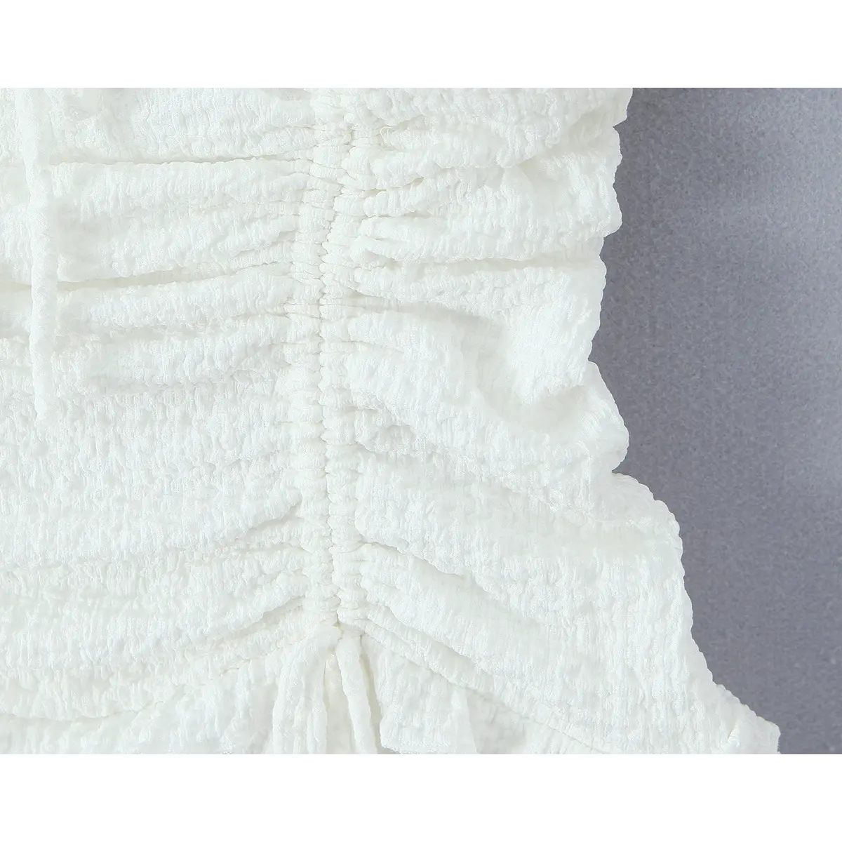 Close-up of the side smocking and texture detail on the white dress.
