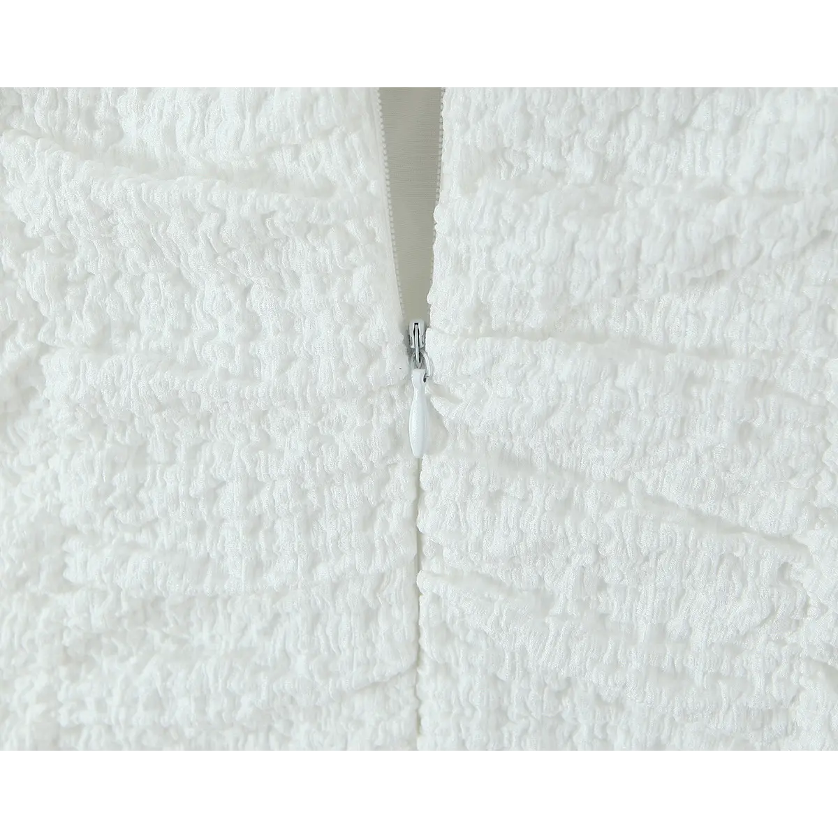 Close-up of the invisible back zipper on the white textured tiered dress.
