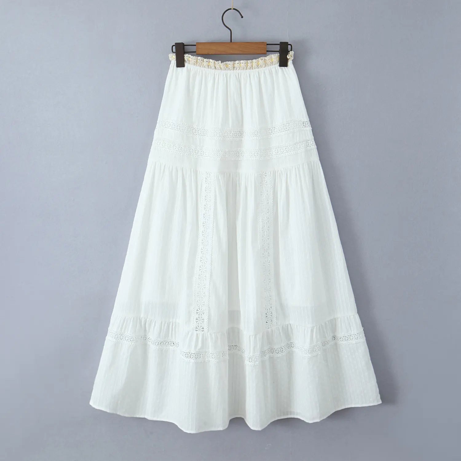 Full back view of a white tiered maxi skirt hanging on a wooden hanger