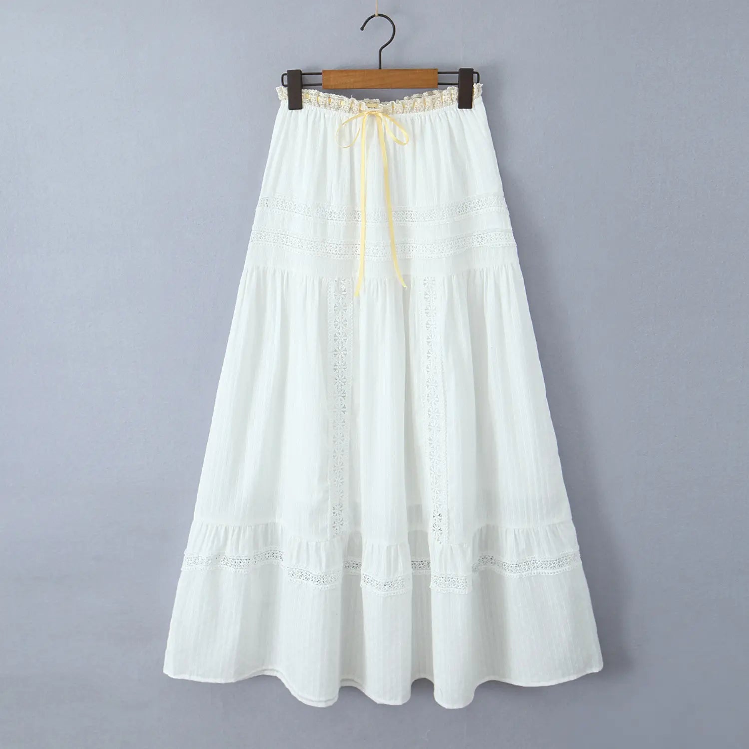 Full front view of a white tiered maxi skirt hanging on a wooden hanger
