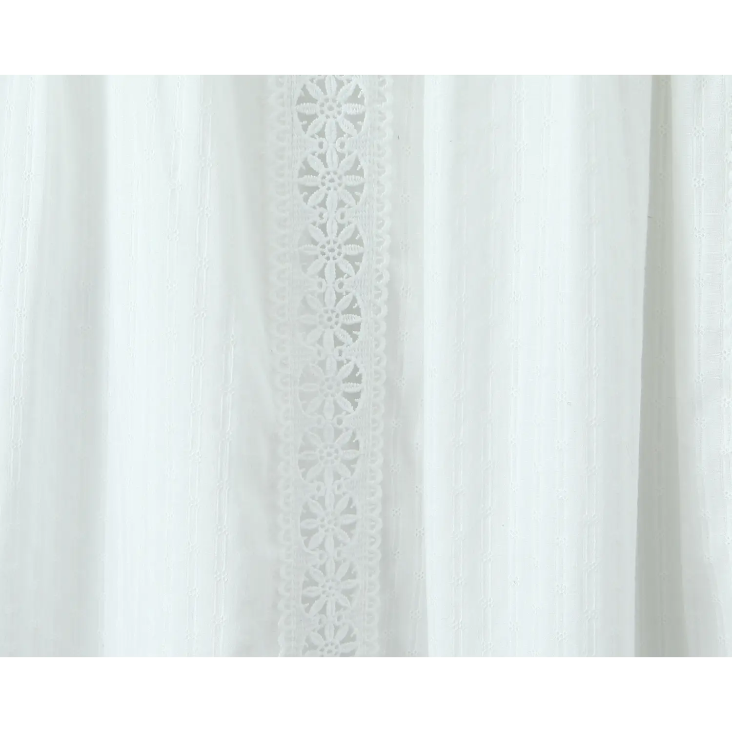 Close-up of the vertical eyelet lace panels running down the side of a white tiered maxi skirt