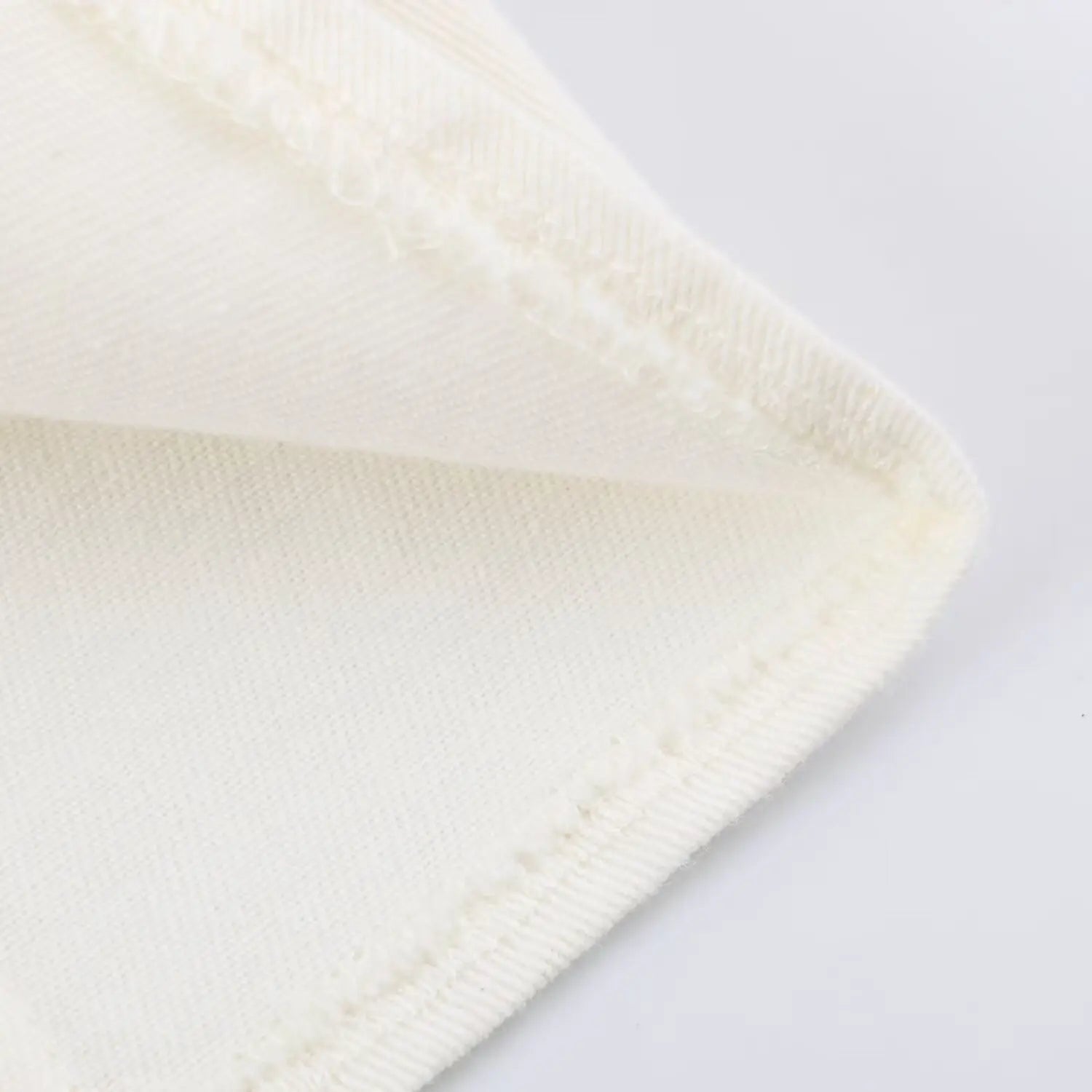 Close up of neat stitched hem and textured twill fabric of white halter mini dress