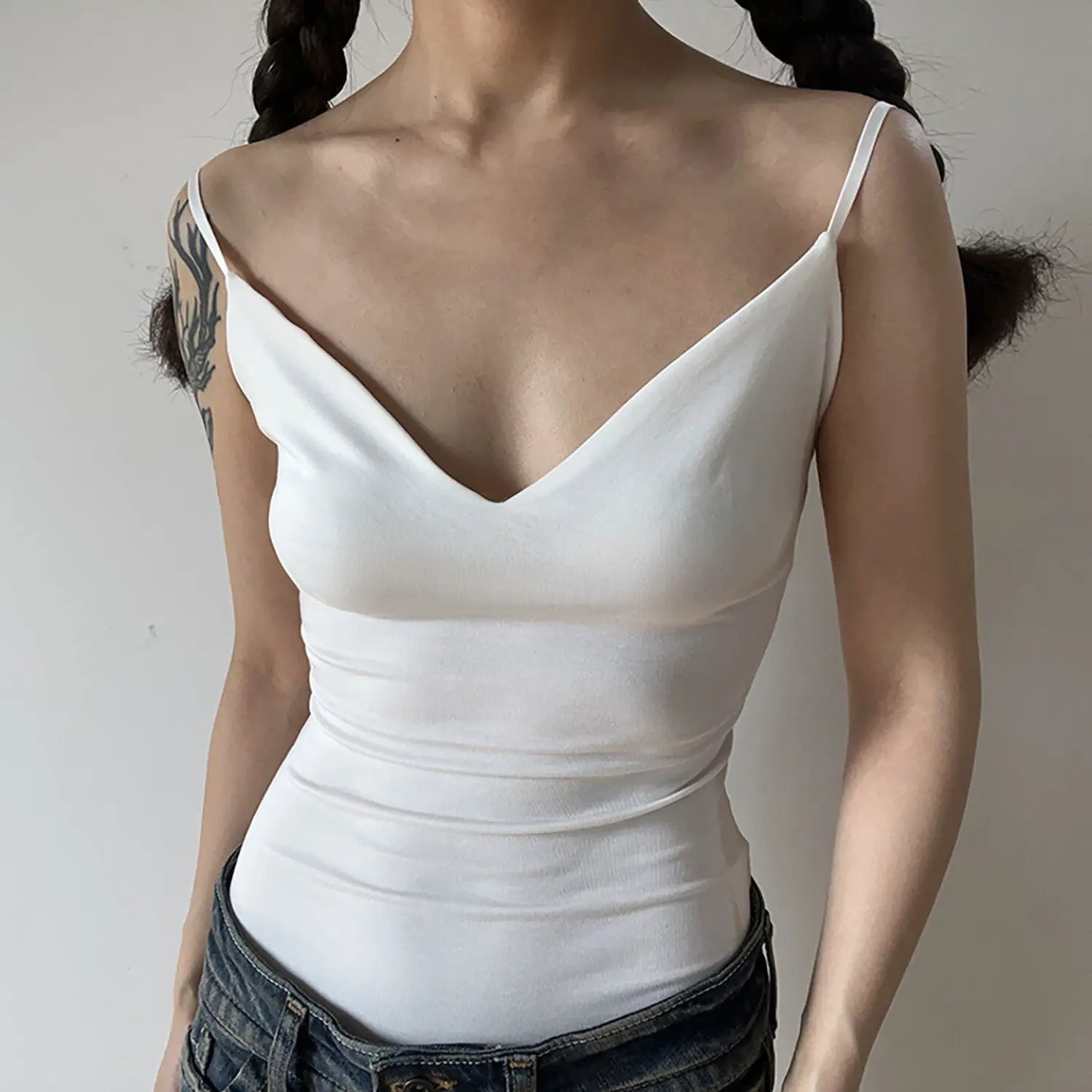 Front shot of women solid white slim fit ribbed cami top, deep V neck thin adjustable spaghetti straps, waist ruched bodycon tank top matched with jeans