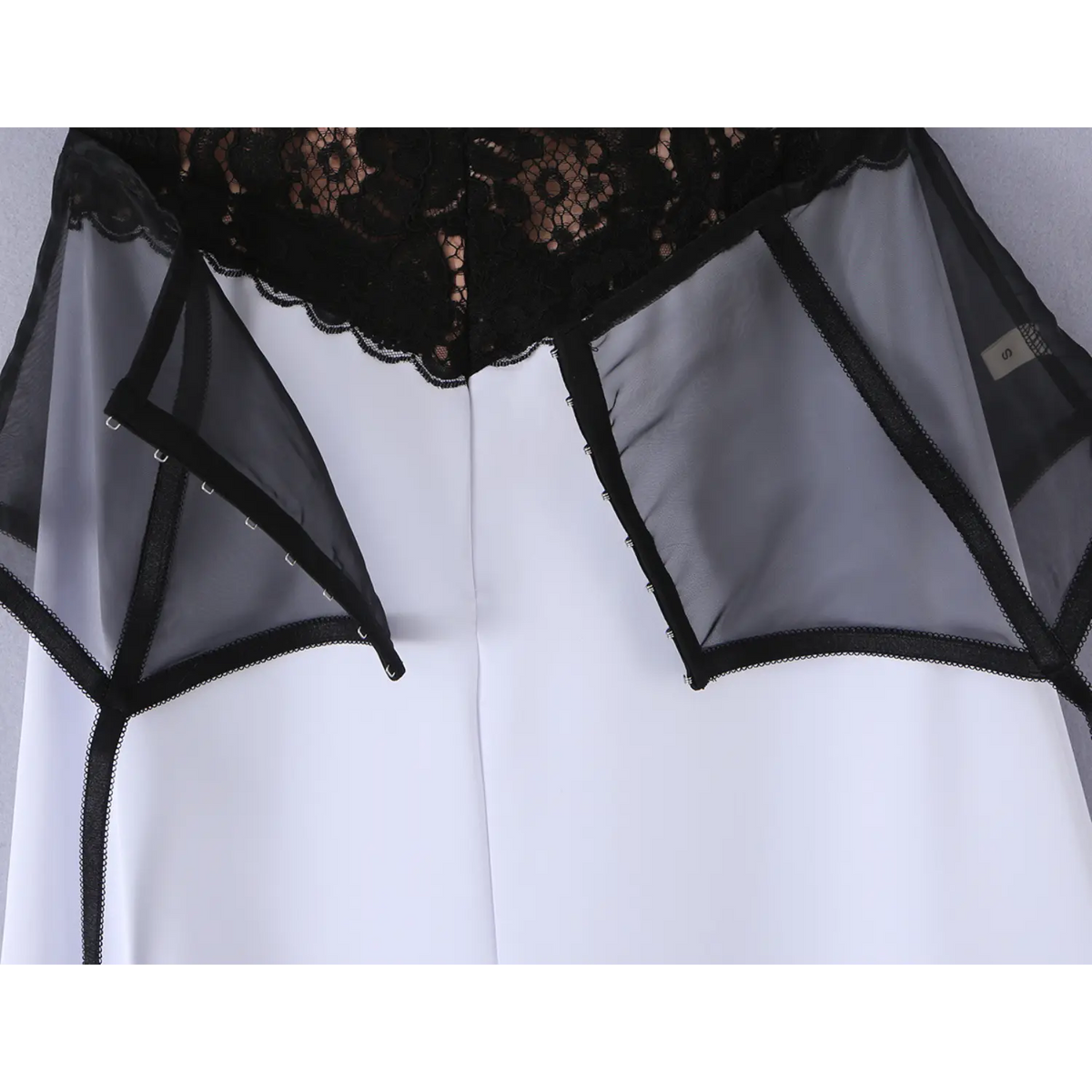Partial close‑up of black mesh peplum overlay at waist