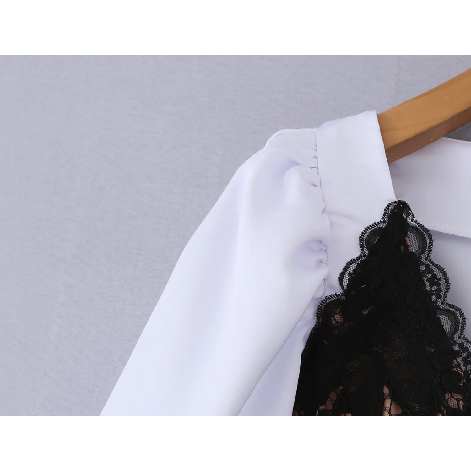 Close‑up of shoulder where white puff sleeve meets black lace overlay
