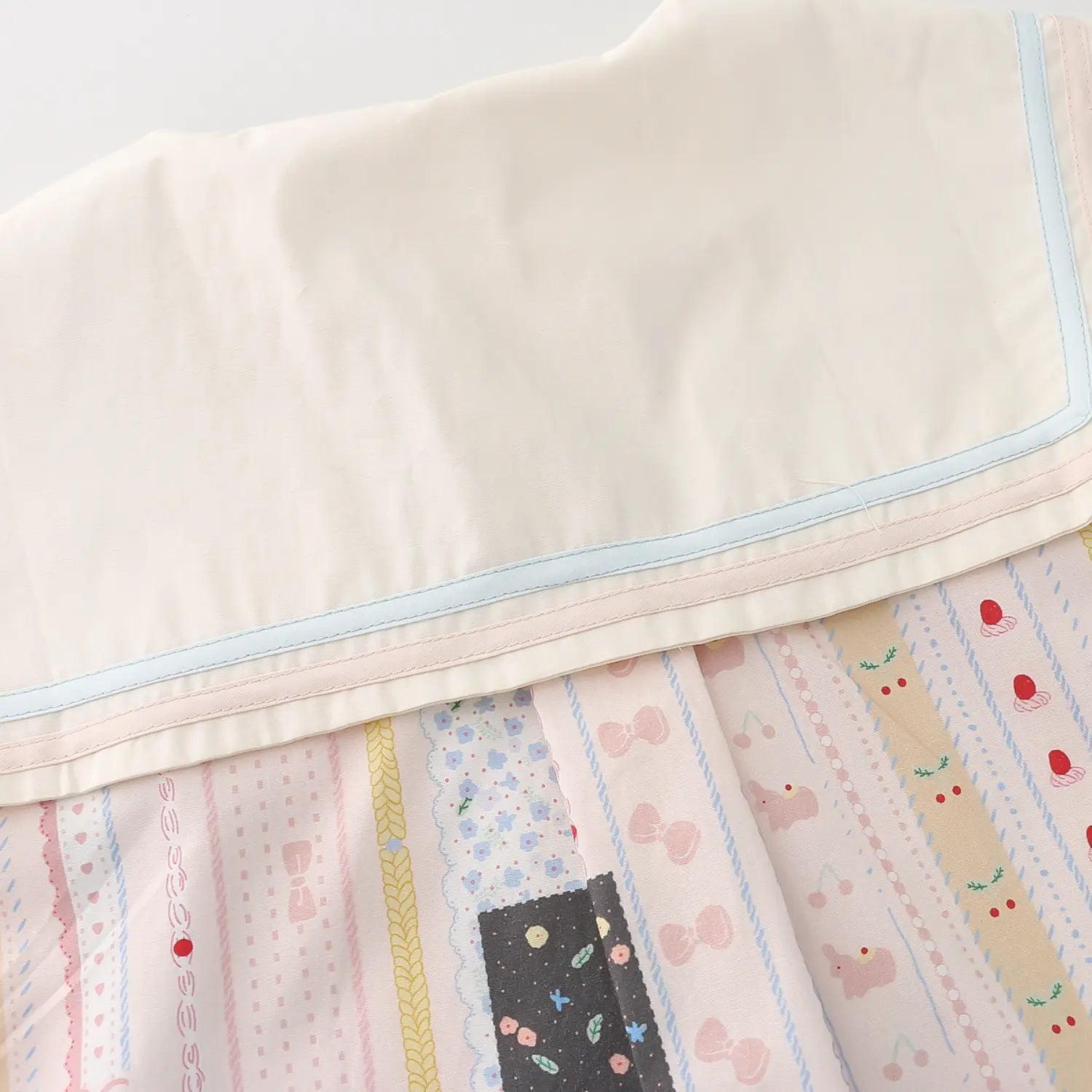 Wide sailor lapel dual contrast piping trim macro close-up, cream lapel matched with parallel light blue & pink thin piping smooth wrinkle-free splicing stitching double layered neck craft shot
