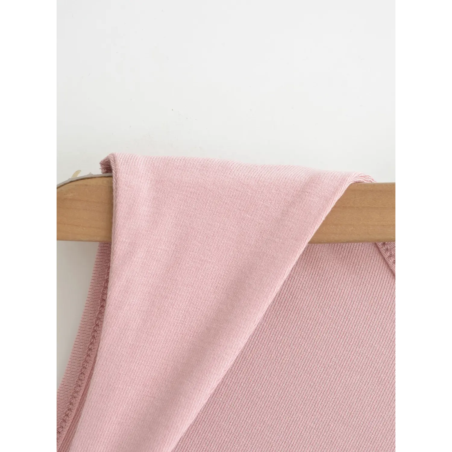 Close-up folded view of wide shoulder strap fabric, soft stretch ribbed material of pink square neck tank top