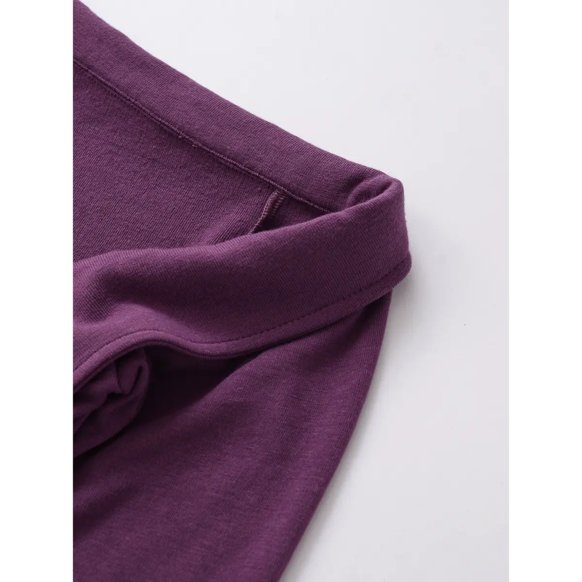  Close-up of the neckline on the purple twist-front top, showing the folded collar detail and smooth knit fabric