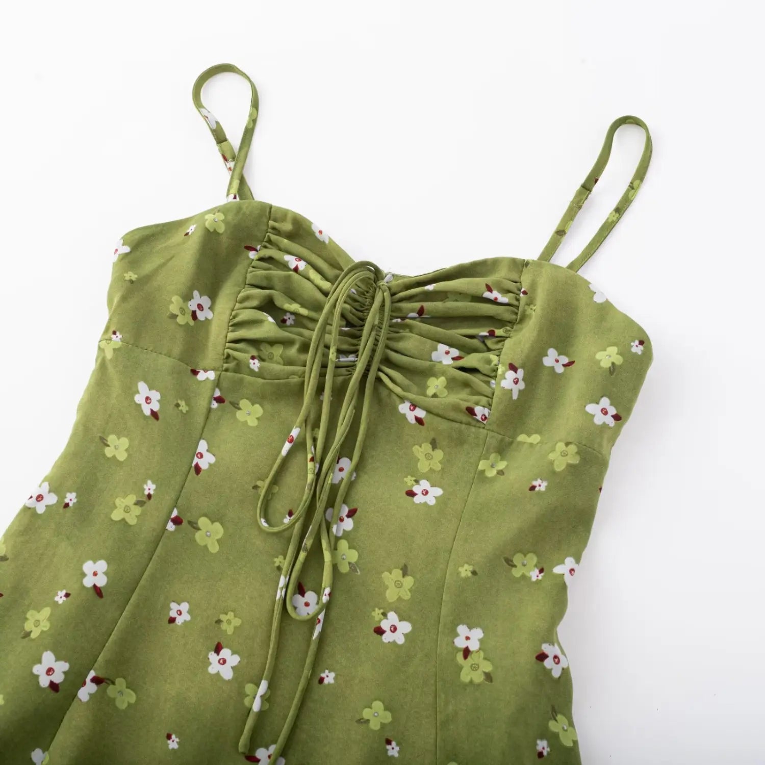 Women avocado green tiny floral drawstring cami mini dress full front flat lay, v-neck gathered adjustable thin straps high waisted a-line mini silhouette white background shot