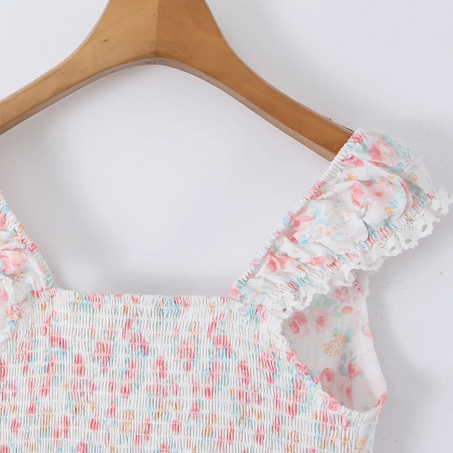 Women pastel floral lace crop top back overall detail, elastic smocked waist lace cap straps hung on wooden hanger