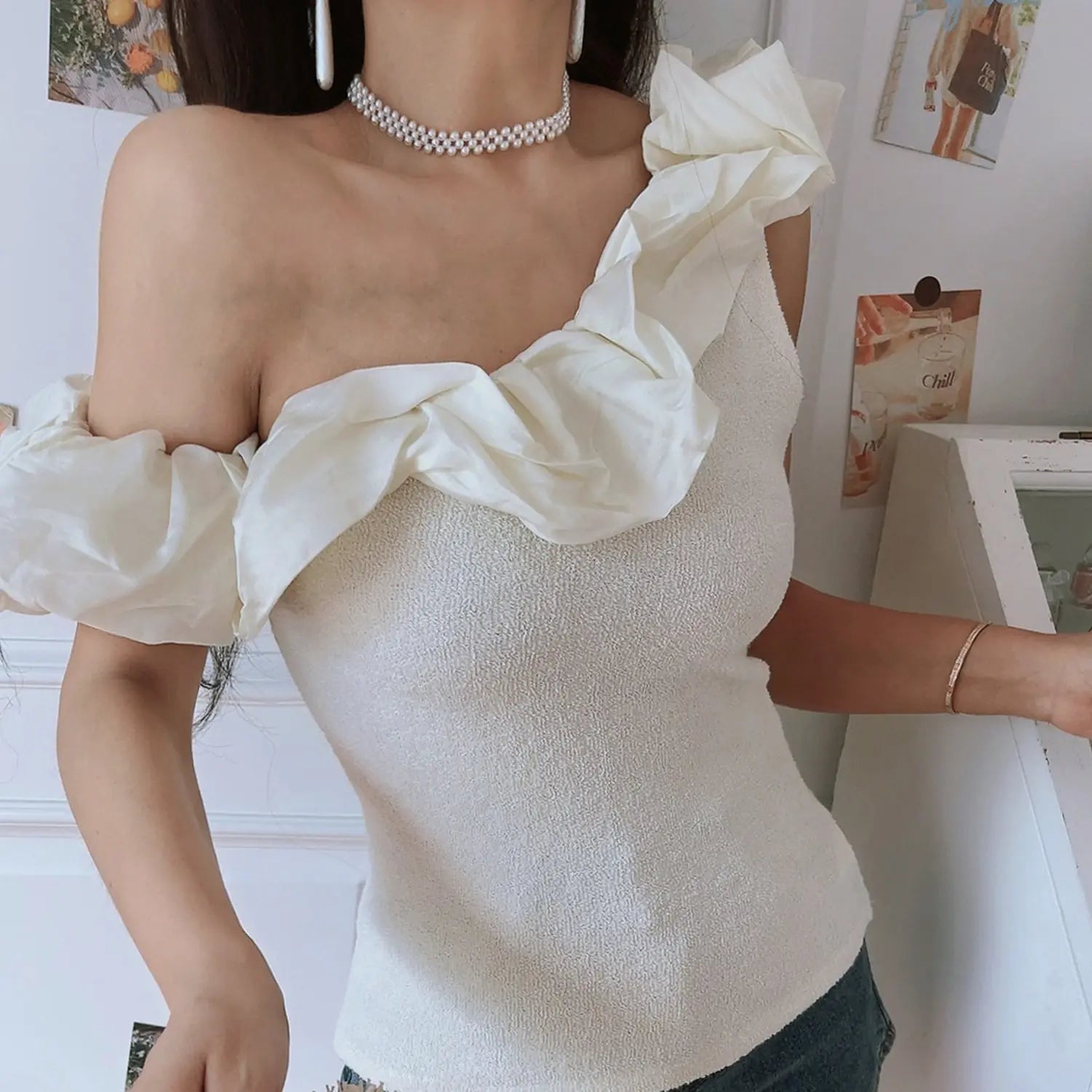 Women off white textured knit one shoulder crop top, diagonal chiffon ruffle fitted cut, model shot against white wall