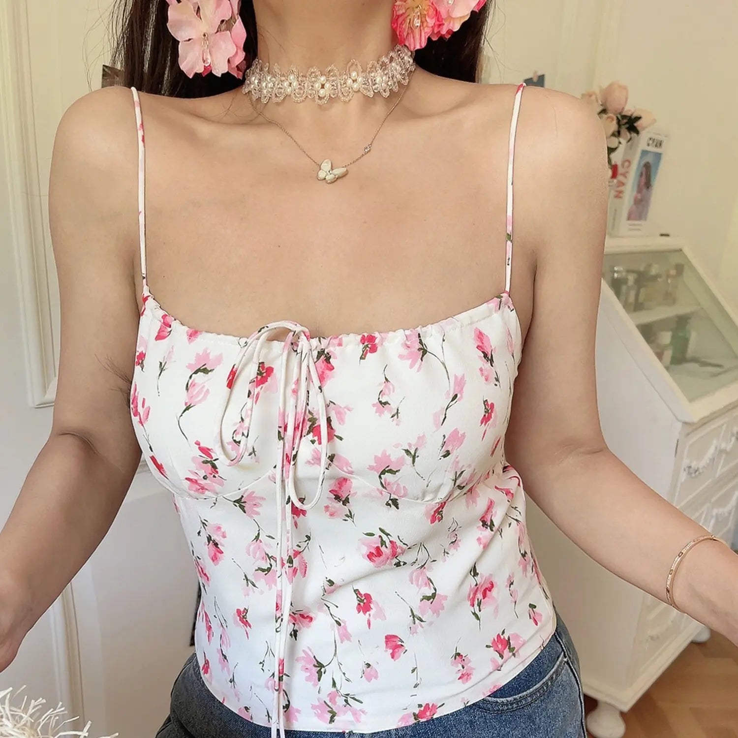 Women white base pink watercolor floral cami crop top, elastic square neck front drawstring tie, indoor half body model shot with denim jeans