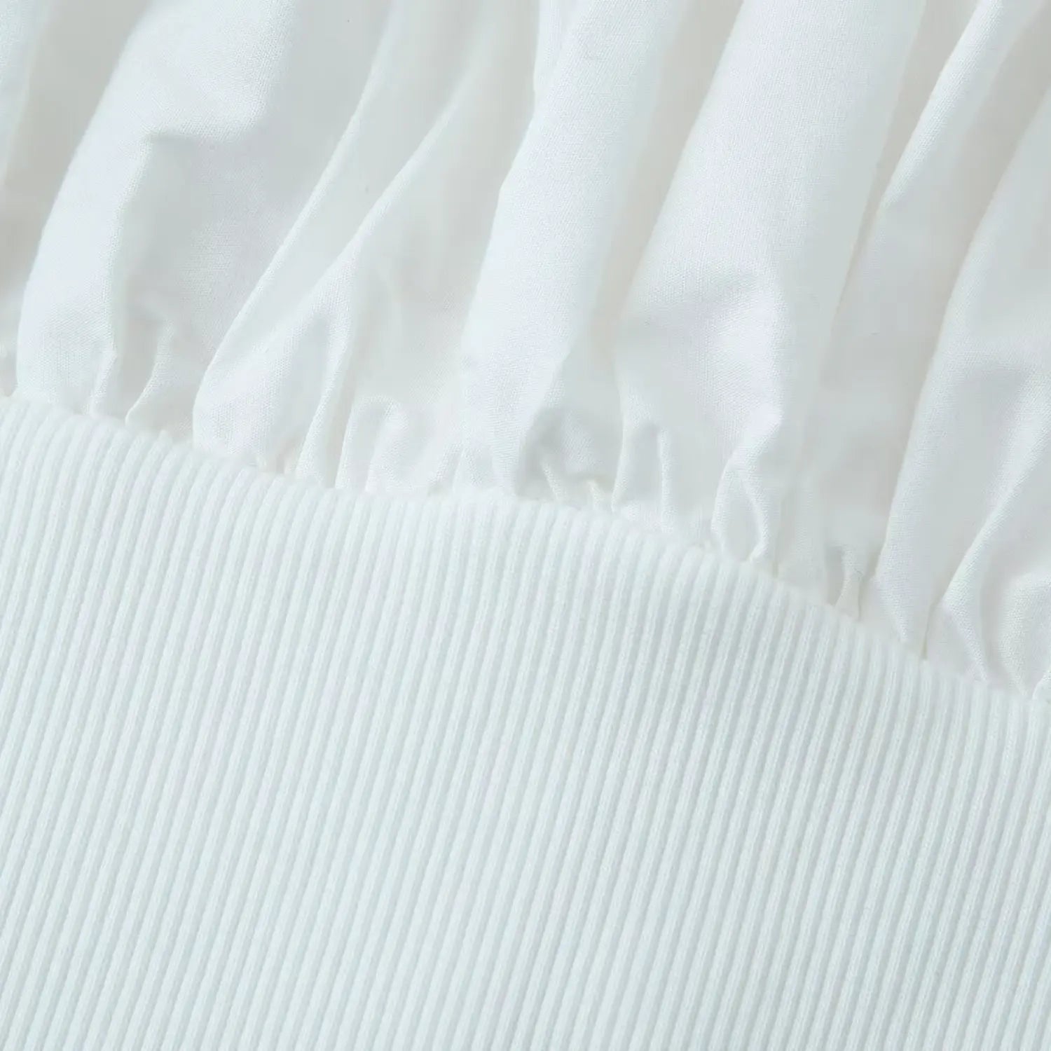 Transition seam between crisp woven bust fabric and vertical rib knit waist fabric