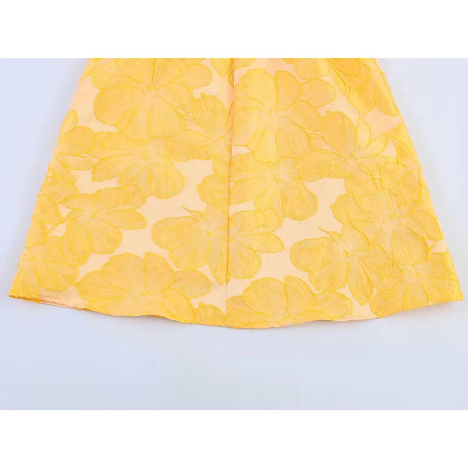 Flat close-up of the skirt hem, showcasing all-over raised yellow floral jacquard texture