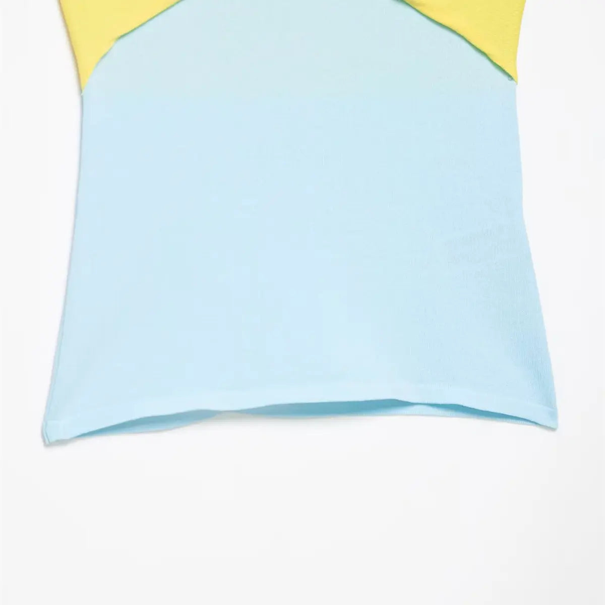 Hem detail of the yellow and blue color-block knit top, showing the light blue ribbed fabric and clean finish