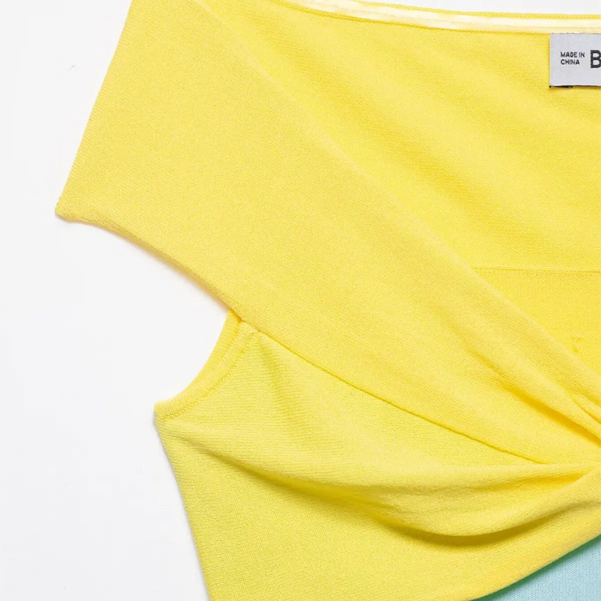 Close-up of the twisted knot detail on the yellow section of the color-block knit top