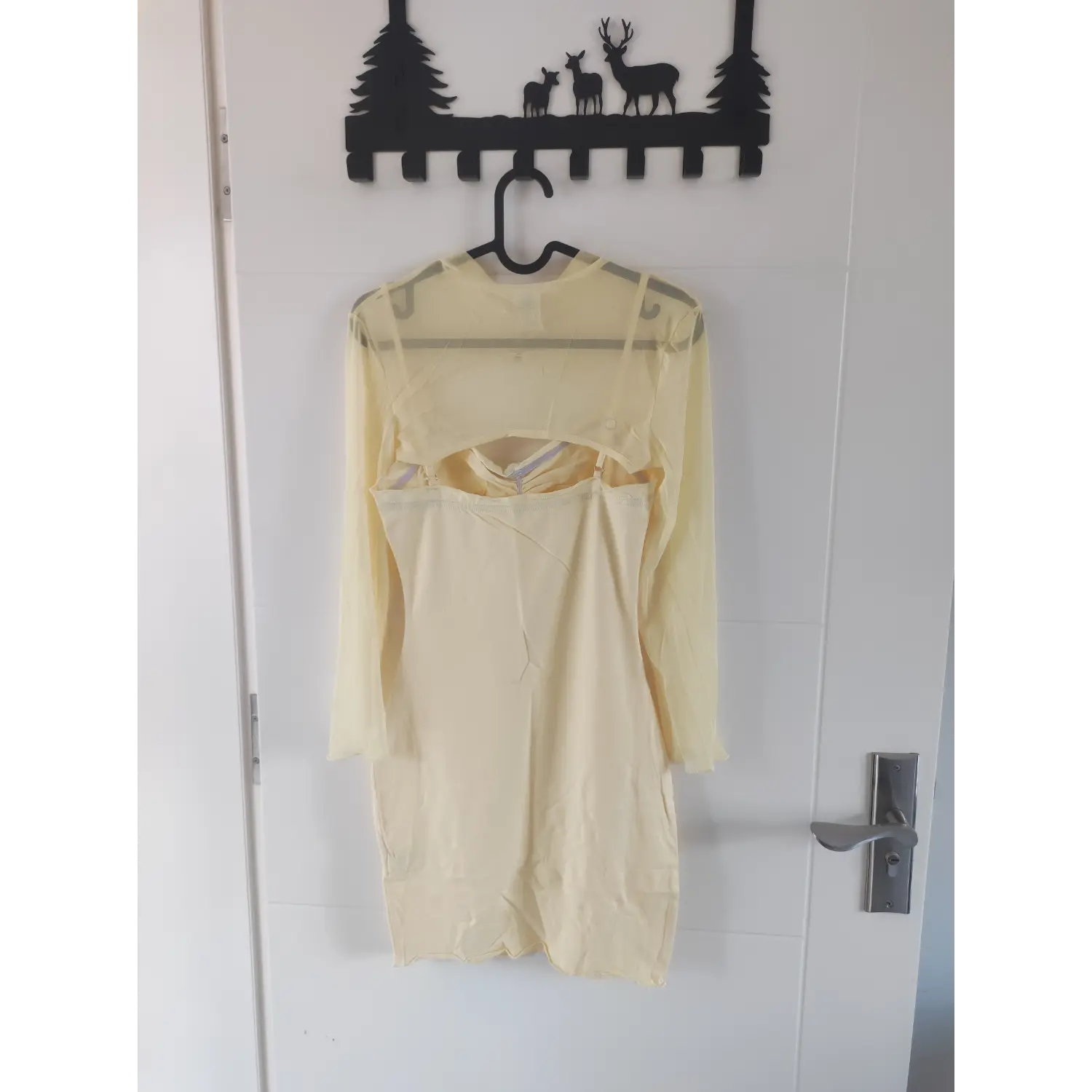 Back hanging shot of yellow mini dress paired with sheer mesh long sleeve cover up