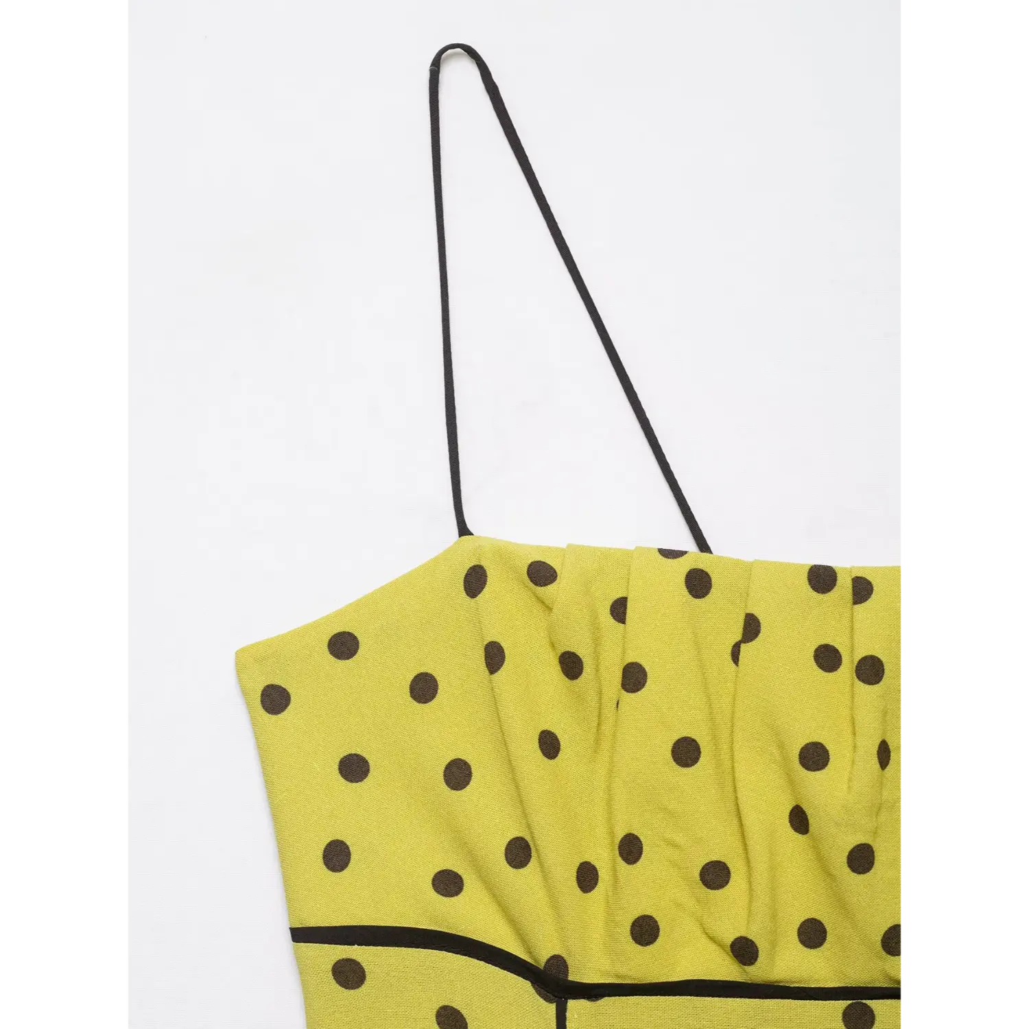 Close-up front bust pleats detail of yellow brown polka dot spaghetti strap midi dress with black trim