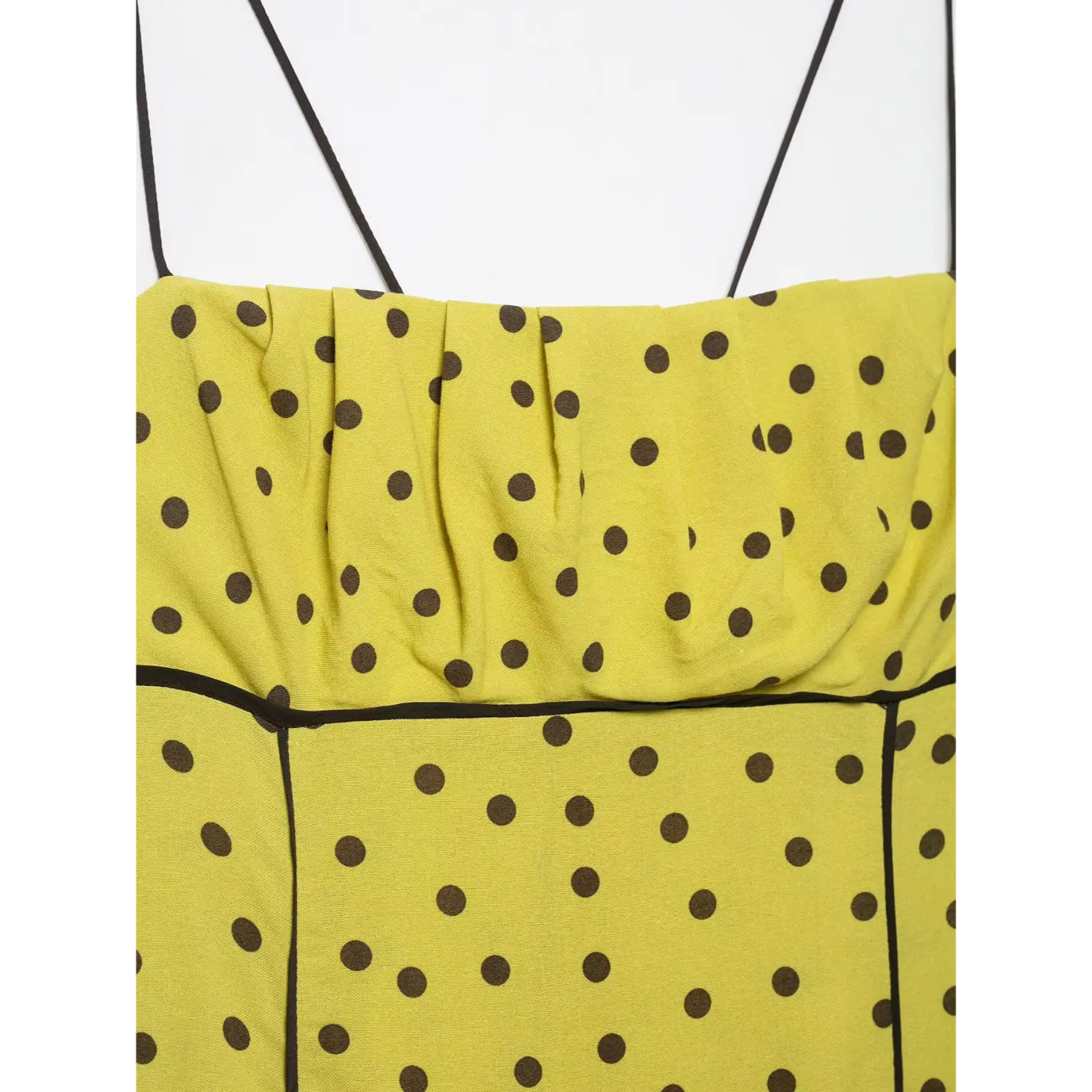 Wide close-up of front horizontal pleats and black waist piping on yellow polka dot midi dress