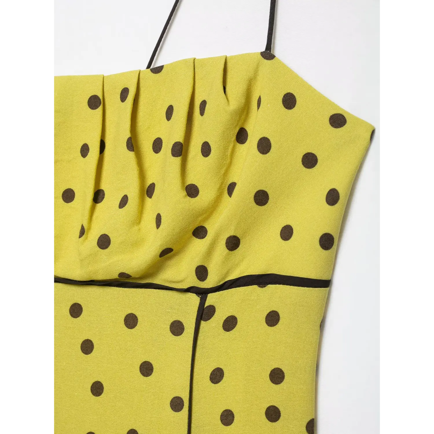 Macro close-up of front ruched bust fabric on yellow brown polka dot spaghetti strap midi dress