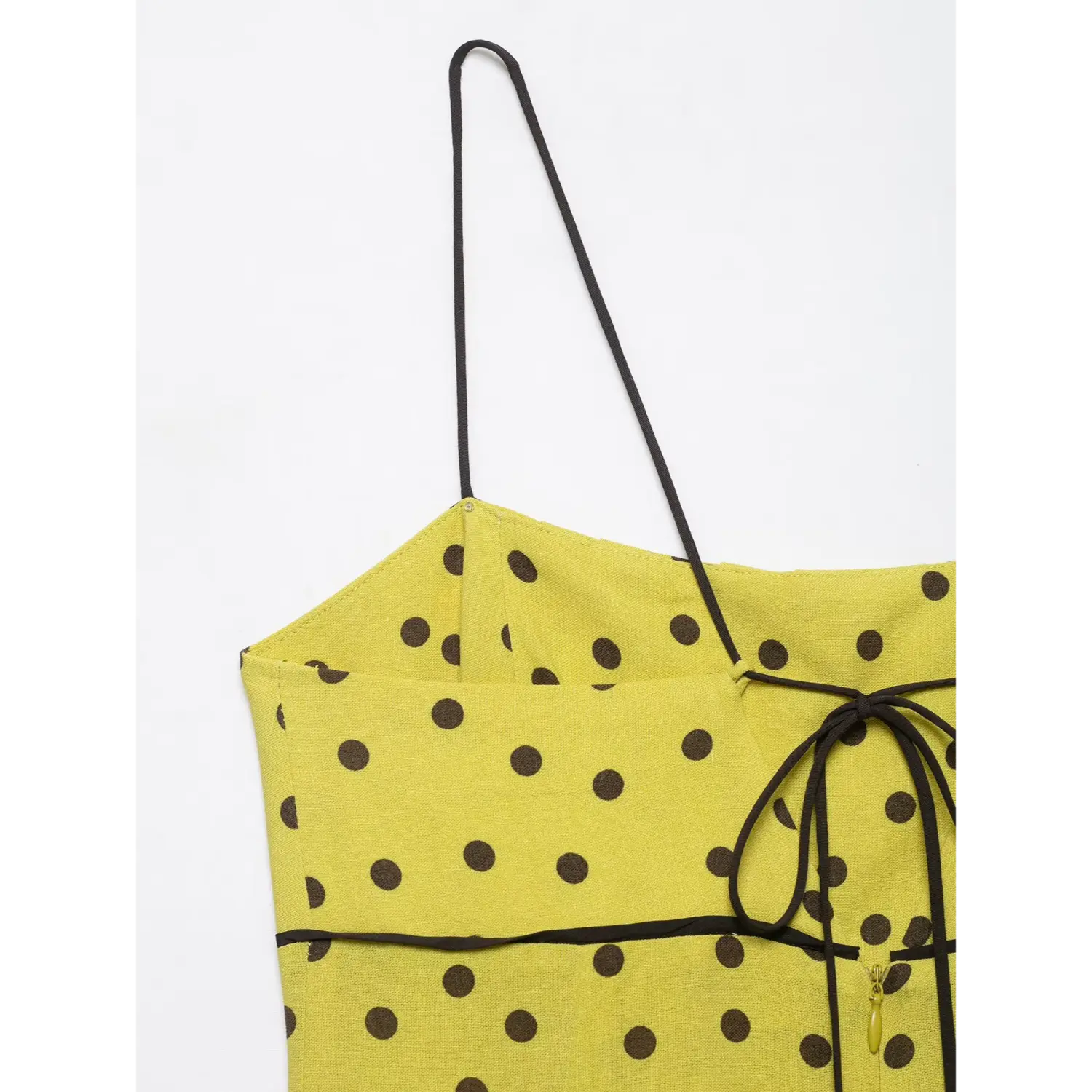 Partial close-up of thin spaghetti strap and back tie detail on yellow brown polka dot midi dress