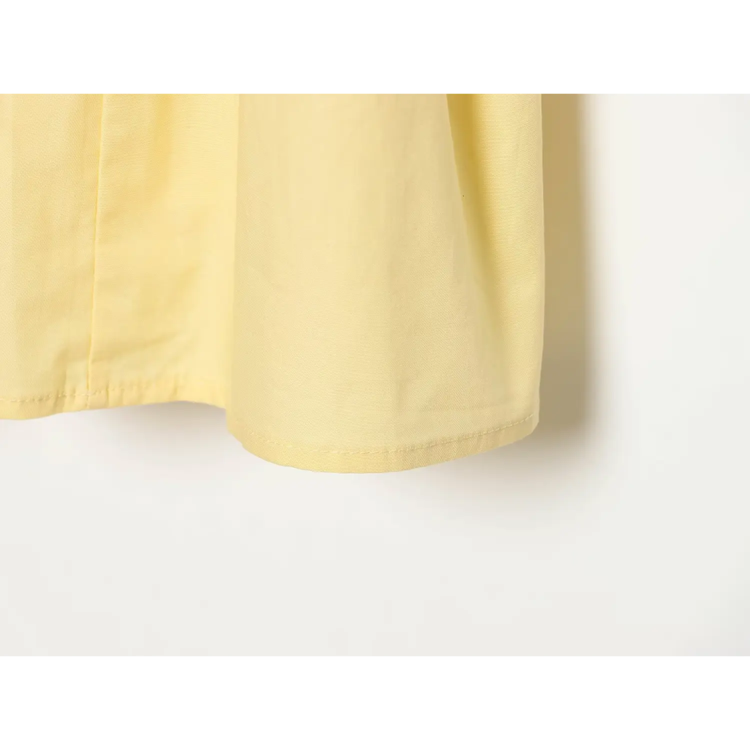 Close‑up of yellow dress skirt hem showing neat finished stitching workmanship