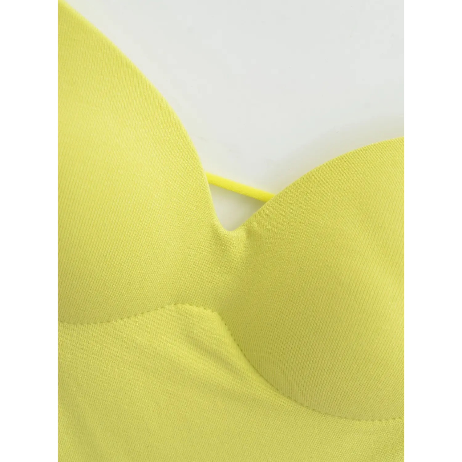 Yellow backless camisole v neck macro flat close-up, molded padded bra surrounding reinforced stitching fine rib knit front thin tie hollow craft white background shot
