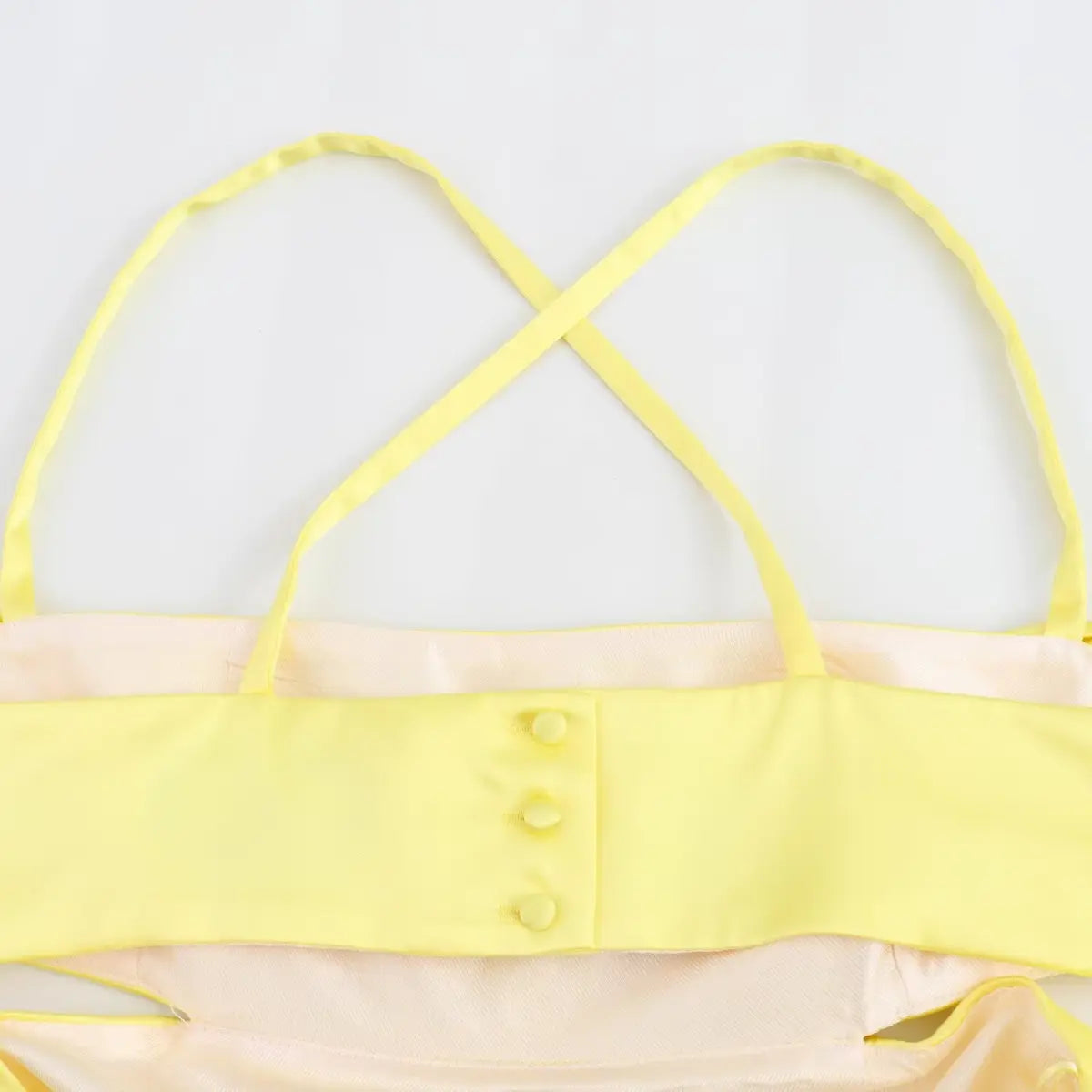 Close-up of the dress's back, showing the button closure on the bodice and crisscross straps.