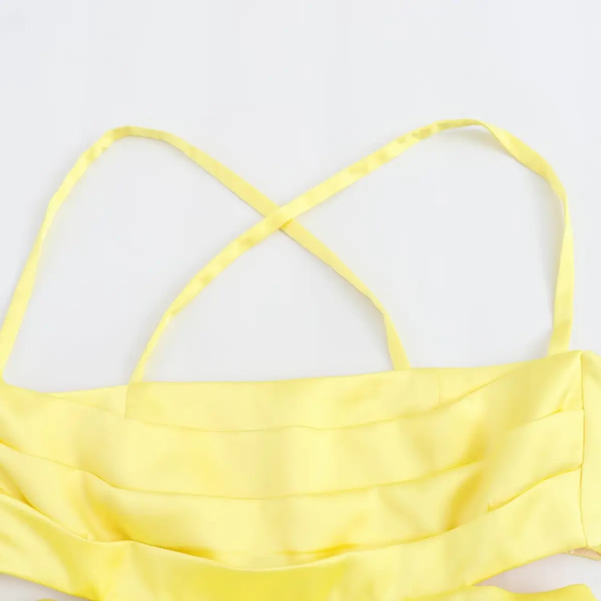 Close-up of the dress's bodice, featuring crisscross spaghetti straps and ruched front detailing.