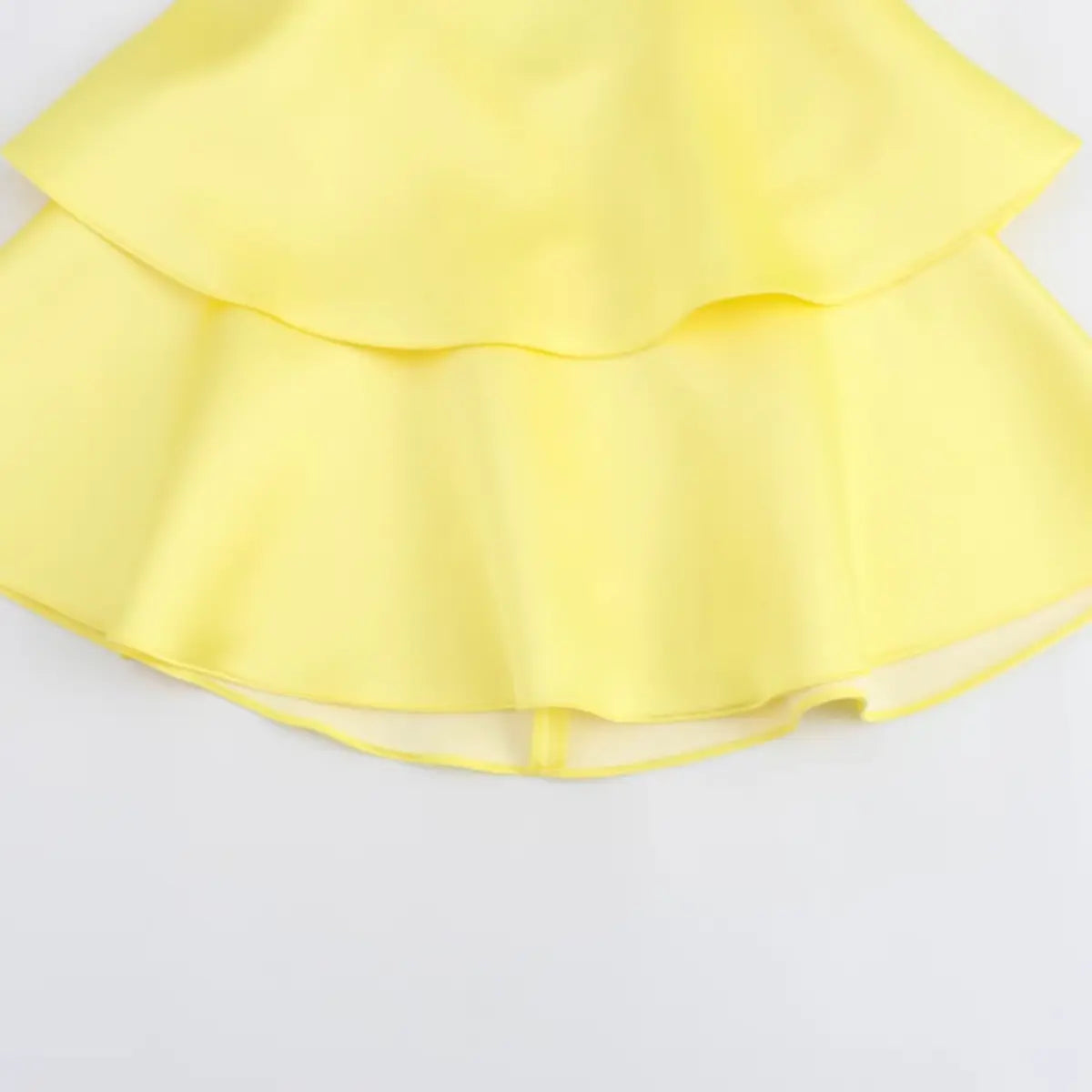 Close-up of the dress's skirt, showing the layered ruffled tiers and smooth fabric texture.