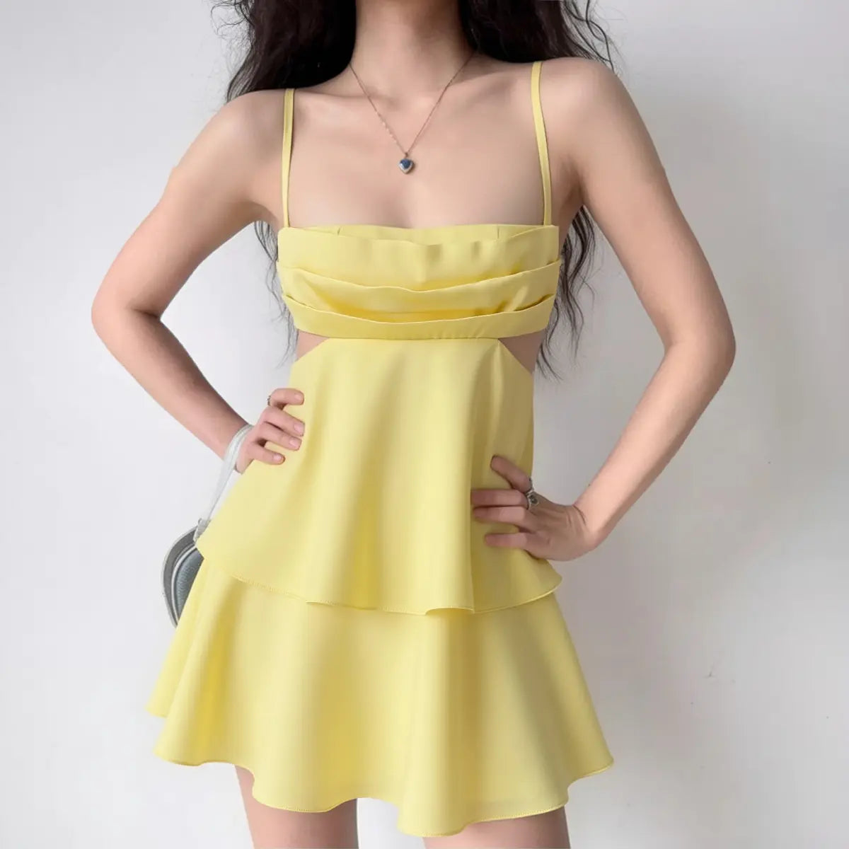 The dress styled on a model, highlighting its structured fabric, waist cutouts, and layered silhouette.