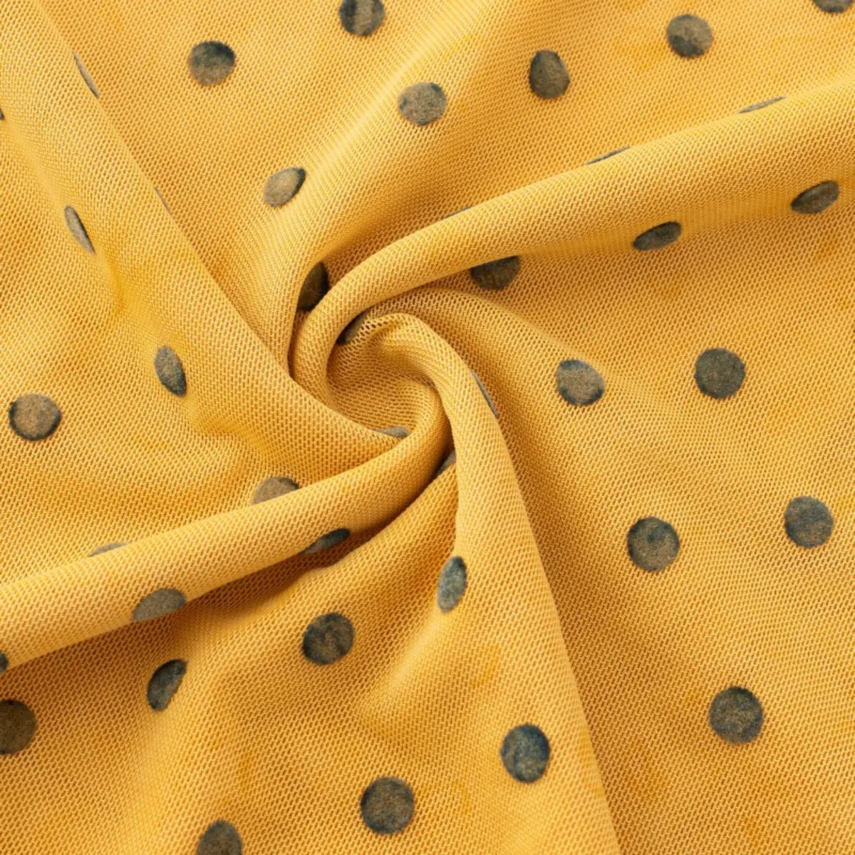 Close-up of the yellow mesh fabric with dark green polka dots, showing the texture and pattern.