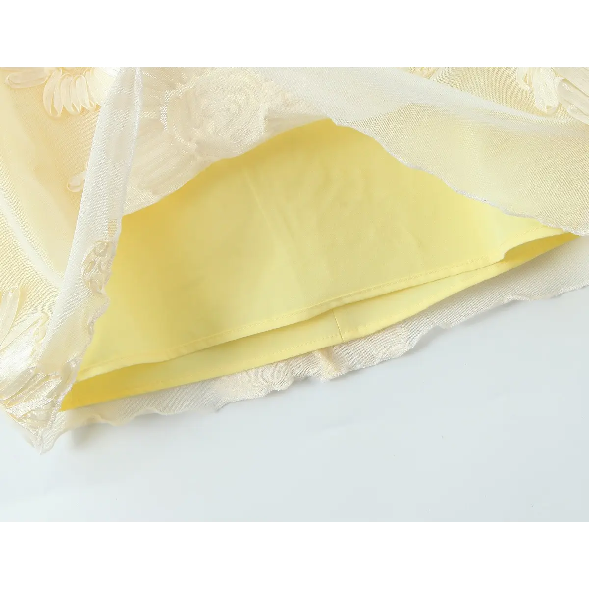 Close-up of the smooth yellow lining and the sheer mesh overlay with embroidery.