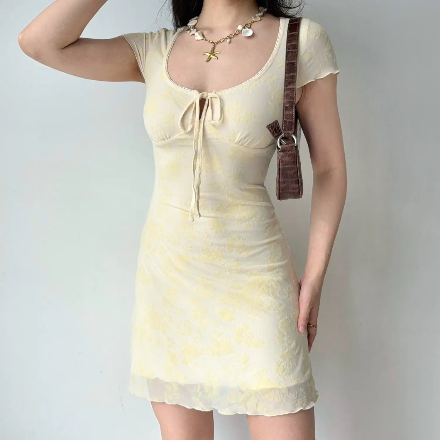Model front pose yellow floral flocked mesh mini dress u‑neck front tie keyhole short ruffle sleeve bodycon short dress