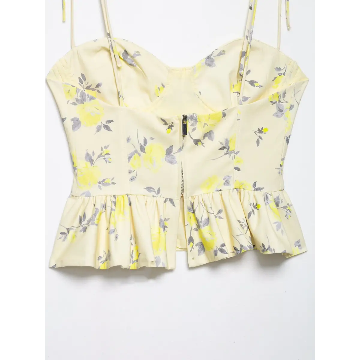 Partial back view showing the center zipper and peplum hem on yellow floral camisole