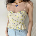 Lifestyle wearing shot of yellow floral print tie-strap peplum corset camisole top, paired with light blue denim jeans