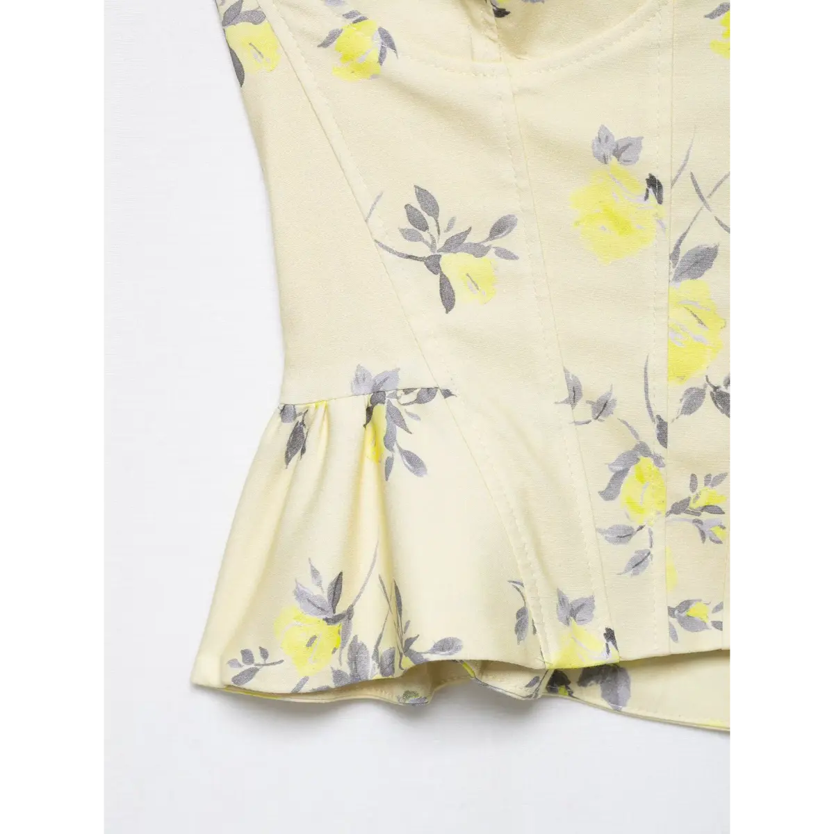 Close-up of the peplum hem on yellow floral print corset camisole, showing the gathered fabric