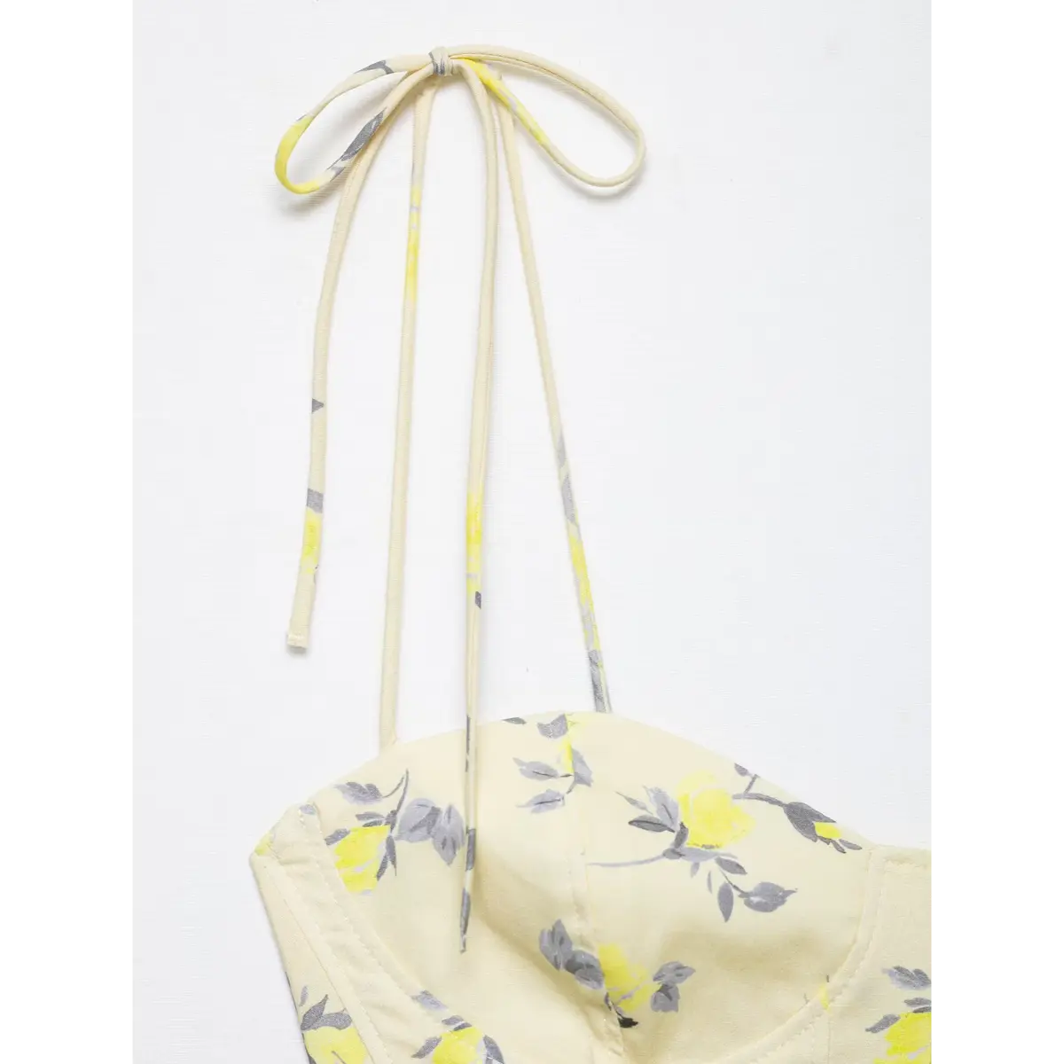 Close-up of the tie strap knot on yellow floral print camisole top