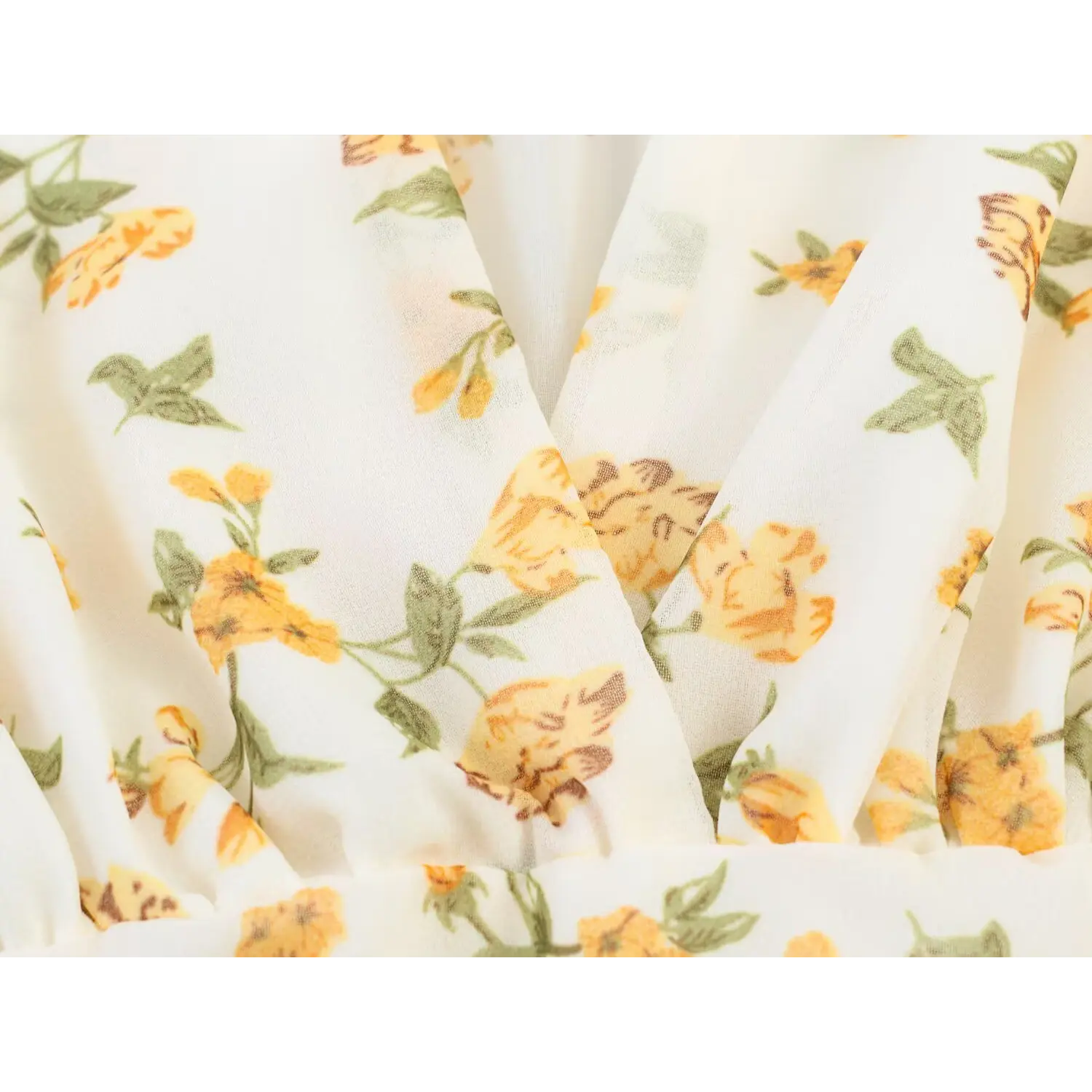 Macro closeup of cream chiffon fabric with yellow flower print and front wrap design