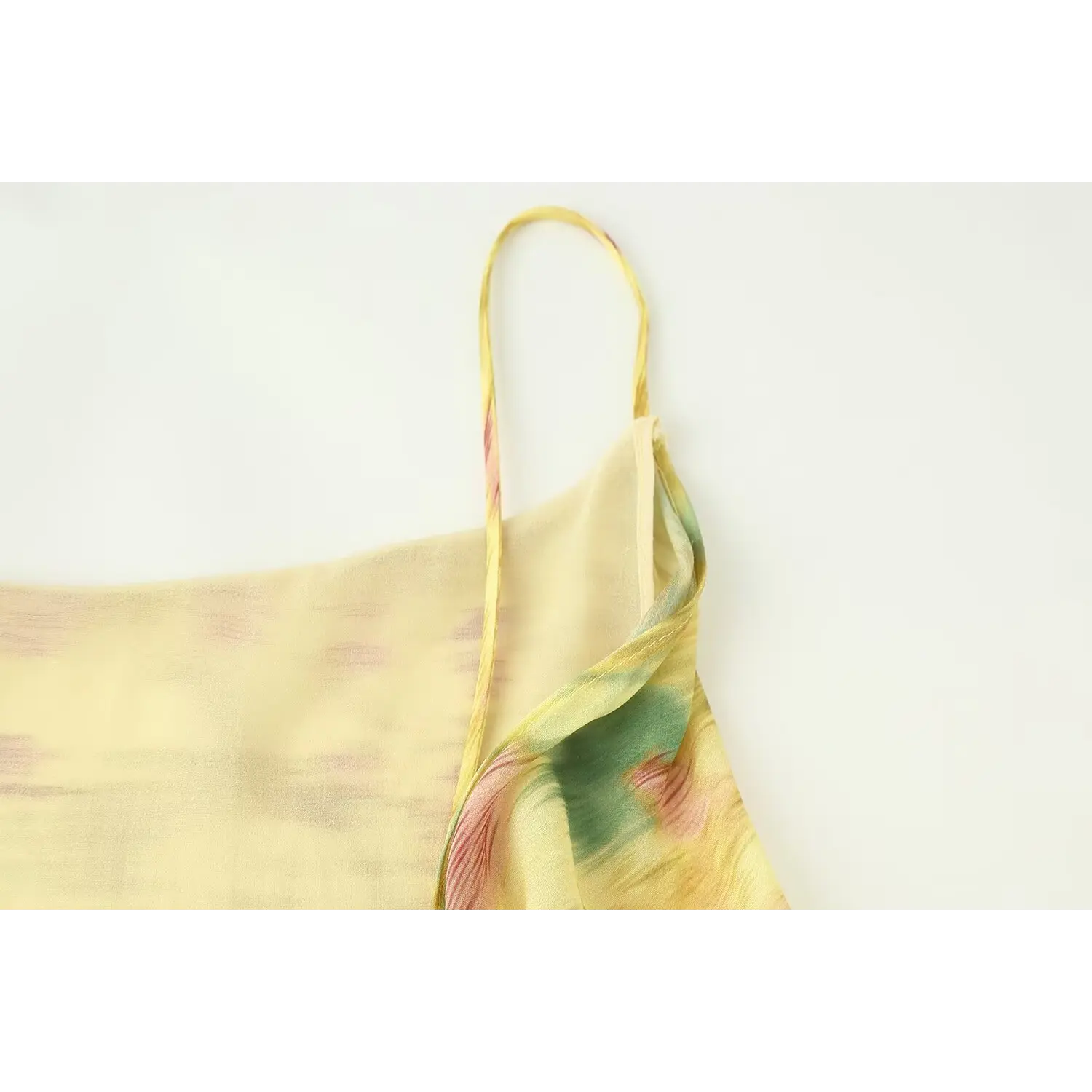 Fabric layering closeup, sheer printed outer chiffon + solid pale yellow smooth lining, neat folded hem binding stitching