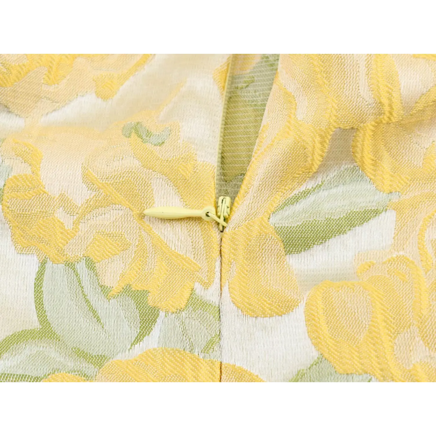 Extreme close-up of matching yellow invisible back zipper on embossed rose fabric