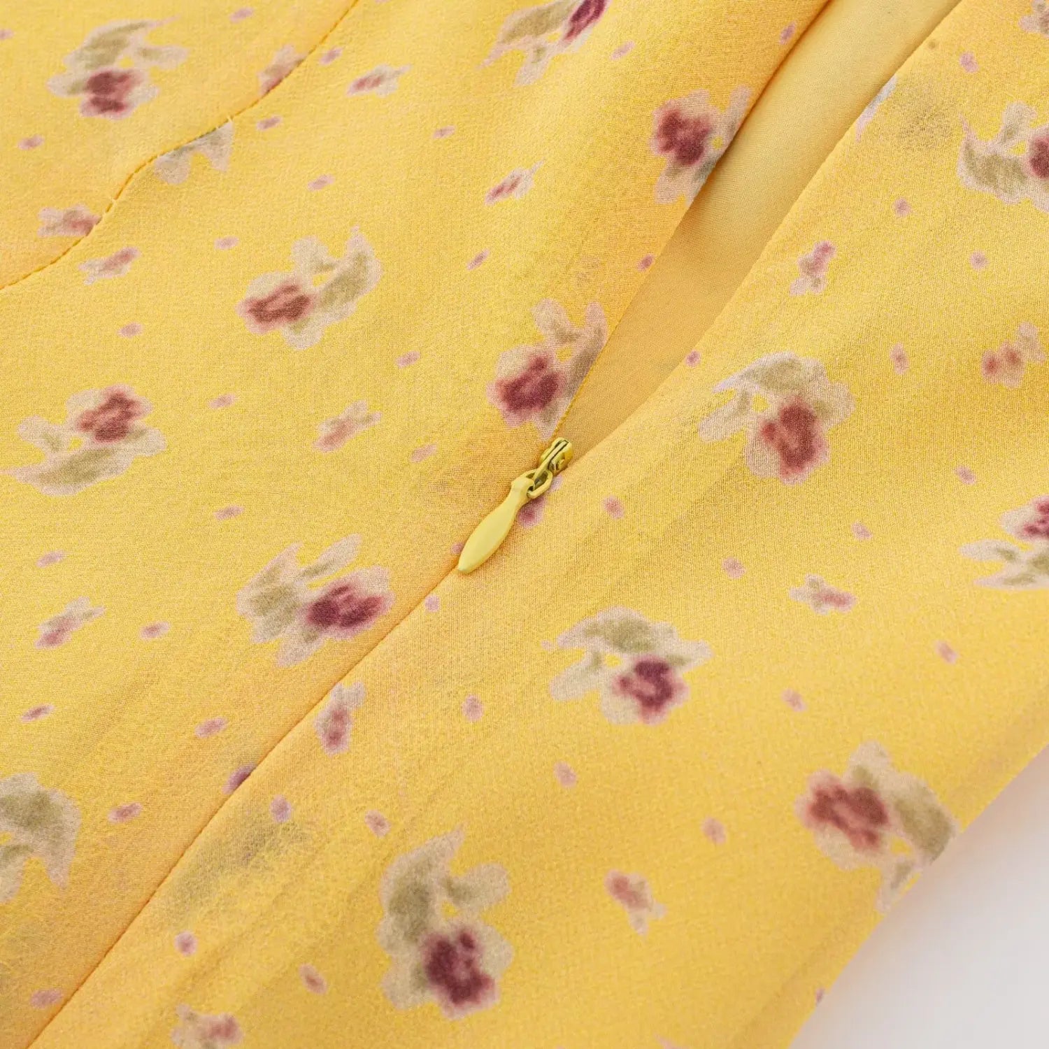 Macro closeup of invisible side zipper on yellow floral chiffon mini dress